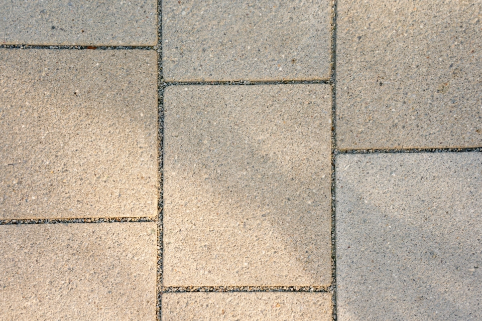 Ein gepflasterter Bereich, bestehend aus klimapositiven Betonsteinen. Der ökologische Flächenbelag hat eine edelstahlkugelgestrahlte, beige und kalkgraue Oberfläche 