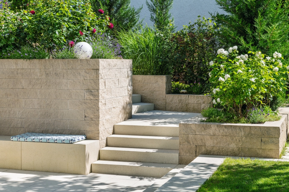 Private modern garden with sandstone-colored terrace and lots of greenery
