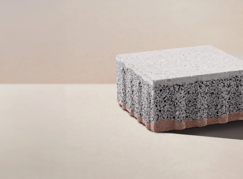 Ein Pflasterstein mit dreischichtigem Aufbau vor einem beigefarbenen Hintergrund