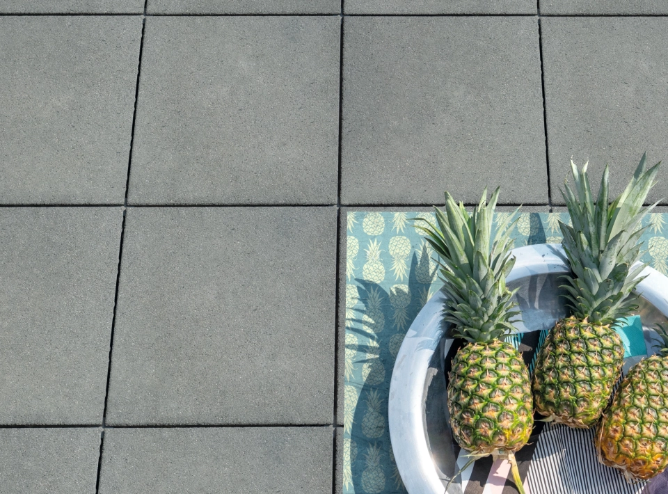 Three pineapples lie on gray patio slabs